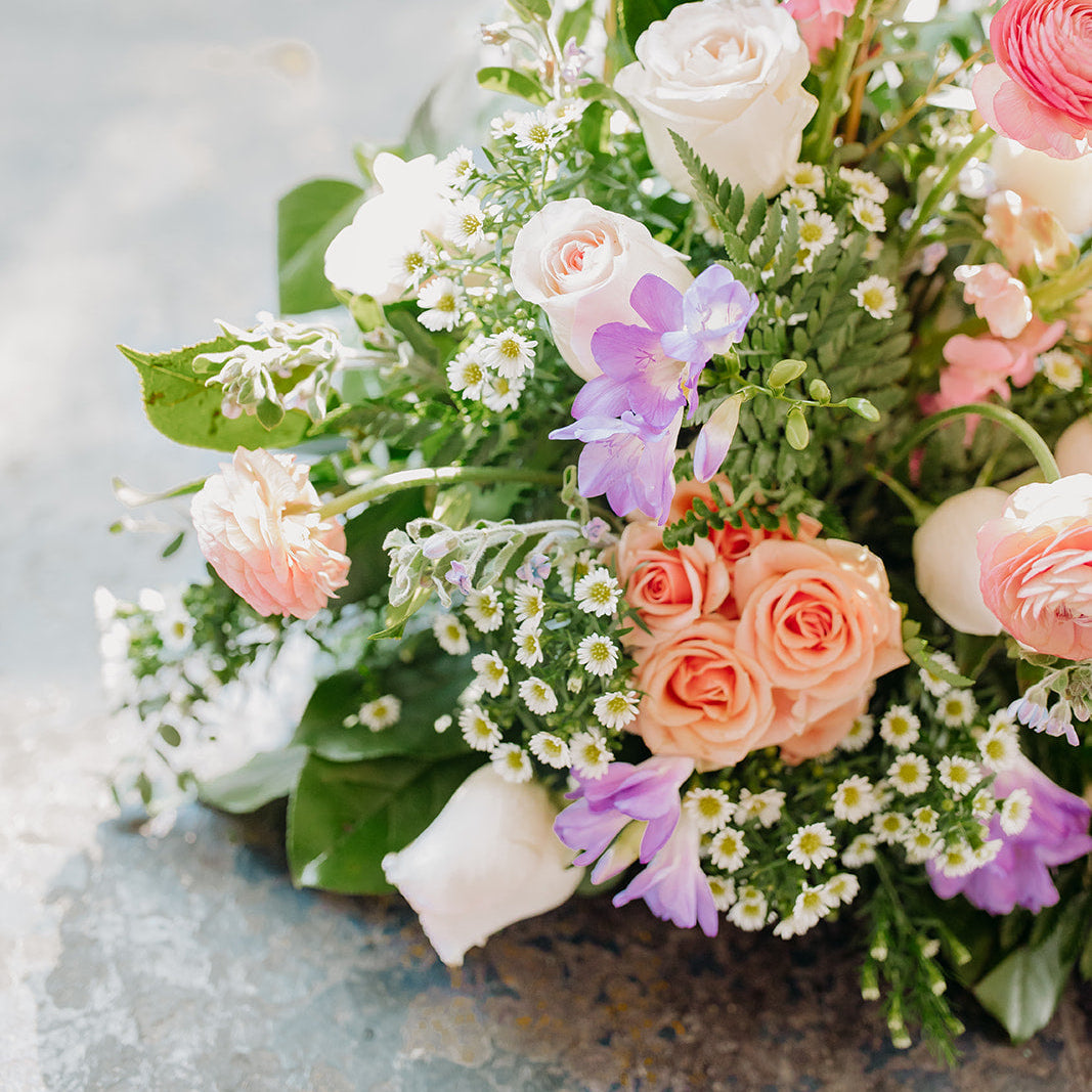 Colorful flower arrangement with a mix of roses and other flowers on a textured surface.
