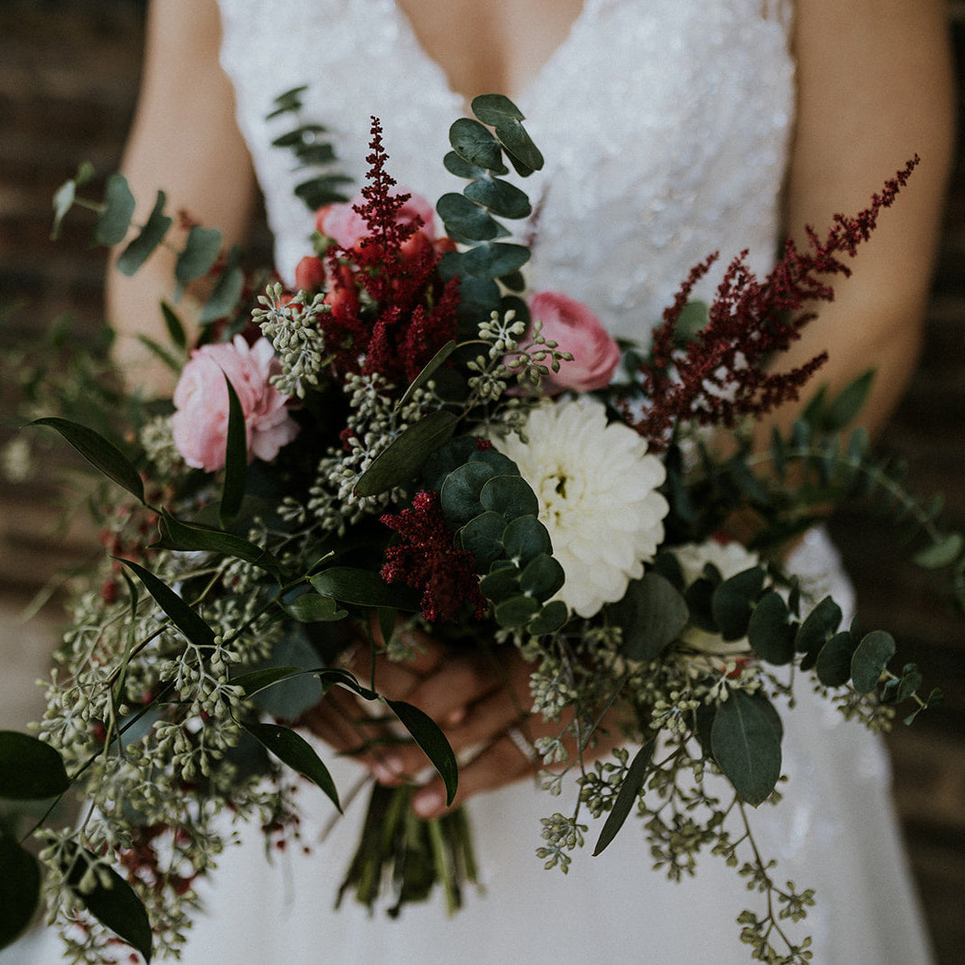 Bouquet of flowers held by a bride wearing a white dress.