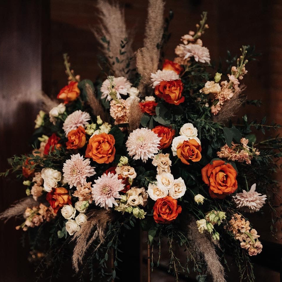Decorative floral arrangement with orange, white, and pink flowers against a dark background